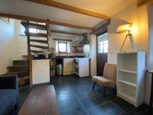 a living room with a table and a kitchen at 9A Viaduct Cottage - the cosiest bolthole in the SW! in Hayle