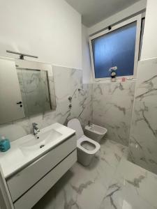 ein Bad mit einem Waschbecken, einem WC und einem Fenster in der Unterkunft Bellissimo appartamento in centro a Sesto Calende in Sesto Calende