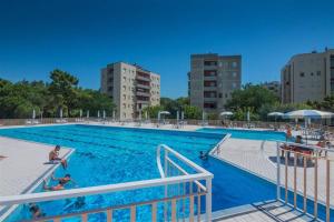 a large swimming pool with people in the water at RESIDENCE Green Beverly con piscina in Lido Adriano