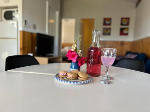 una mesa con una botella de vino y galletas y una copa en Selwyn Cottage 3, en Tumbarumba