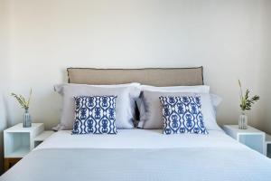 圖羅斯的住宿－Luxury Mykonos Villa - Stunning Seaviews - 4 Bedrooms - Jacuzzi - Agia Sofia Villa，一间卧室配有一张带蓝色和白色枕头的床