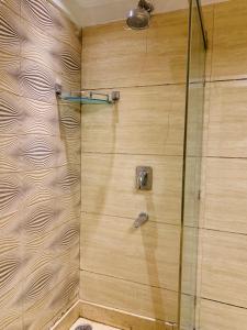 een badkamer met een douche en een houten muur bij Metropolis Tourist Home Paharganj in New Delhi