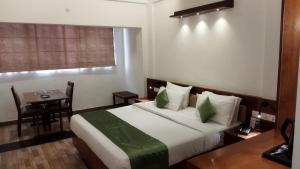une chambre d'hôtel avec un lit, une table et une fenêtre dans l'établissement Queens Tourist Home, à Badagara