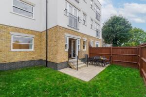 a house with a patio with a table and chairs at Modern 2 Bed Oasis - Private parking & Garden in Windsor