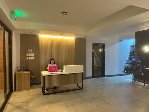 a woman sitting at a desk in an office with a laptop at D'ELEMENTS HOTEL AND DORMITORY in Laoag