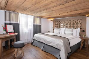 sypialnia z dużym łóżkiem i drewnianym sufitem w obiekcie Appenzeller Huus Bären w mieście Gonten