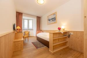 a bedroom with a bed and a desk and a chair at Hotel Krone in Matrei am Brenner