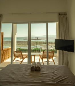 um quarto com uma cama e vista para a praia em The Peak Surf House em Huu
