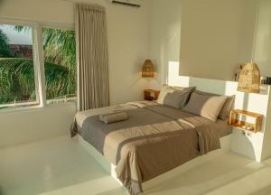 a bedroom with a bed and a large window at The Peak Surf House in Huu