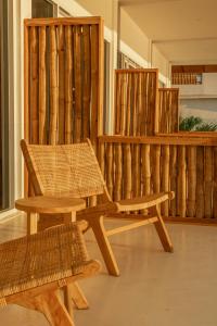 a wooden bench and a chair in front of a fence at The Peak Surf House in Huu