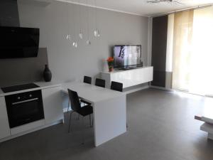 eine weiße Küche mit einem Tisch und einem TV in der Unterkunft Apartment Gizycko in Giżycko