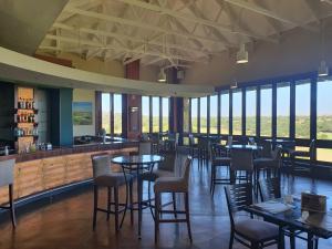 un restaurante con mesas, sillas y ventanas en Elements Golf Reserve House 303, en Moheme