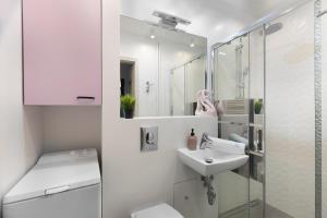 a white bathroom with a sink and a toilet at Elite Apartments Brzeźno Family in Gdańsk