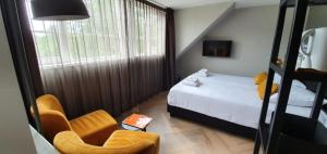 a small bedroom with a bed and two chairs at B&B Dennenbos in Oostkapelle