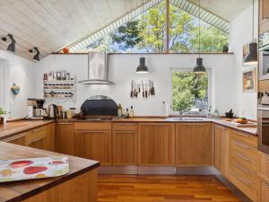 una cocina con armarios de madera y una gran ventana en Holiday Home Amina - all inclusive - 1-1km from the sea by Interhome, en Rørvig