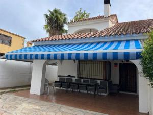 een gebouw met een blauwe luifel met tafels en stoelen bij Diamante en Cambrils Costa Dorada in Cambrils