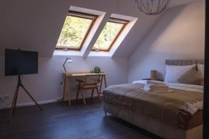 a bedroom with a bed and a desk and two windows at Apartment am Kurpark mit traumhafter Terrasse in Bad Ems