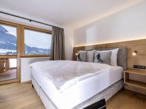 a bedroom with a large white bed and a large window at Apartment Penthouse large Bergblick 19 by Interhome in Söll