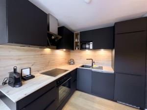 ゼルにあるApartment Superior Bergblick 2 by Interhomeのキッチン(黒いキャビネット、カウンタートップ付)