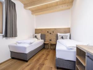 two beds in a room with white walls and wooden floors at Apartment Apartments Austria-18 by Interhome in Söll