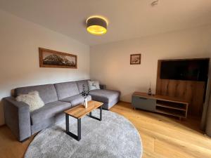 a living room with a gray couch and a table at Apartment Comfort Bergblick 04 by Interhome in Söll