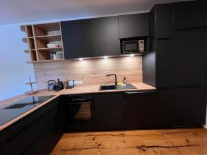 a kitchen with black cabinets and a sink and a microwave at Apartment Apartments Austria-5 by Interhome in Söll