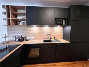 a kitchen with black cabinets and a sink at Apartment Apartments Austria-5 by Interhome in Söll