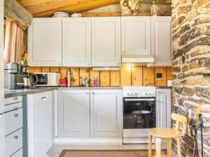 a kitchen with white cabinets and a brick wall at Holiday Home Kelokoto by Interhome in Saariselka