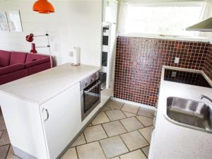 a kitchen with a sink and a red tiled wall at Holiday Home Thara - 100m from the sea in SE Jutland by Interhome in Sønderby