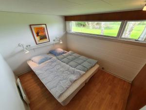 a small bedroom with a bed in a room with two windows at Holiday Home Thara - 100m from the sea in SE Jutland by Interhome in Sønderby
