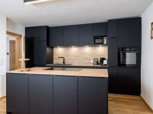 a kitchen with black cabinets and a sink at Apartment Family 03 by Interhome in Söll