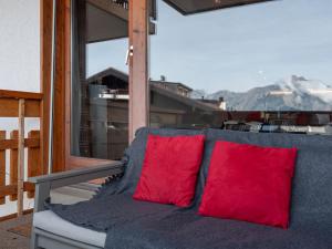 a couch with two red pillows on a balcony at Apartment Victoria 1 D2 by Interhome in Nendaz