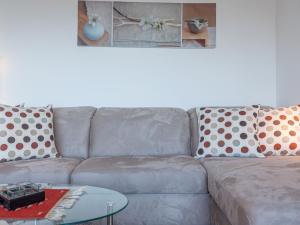 a gray couch with polka dot pillows and a table at Apartment Olympic C7 by Interhome in Nendaz