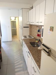 Una cocina con gabinetes blancos y un fregadero. en TAMBO LIBERTADOR, en San Juan
