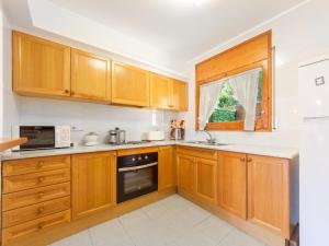 a kitchen with wooden cabinets and a microwave at Apartment Melis III by Interhome in Pals