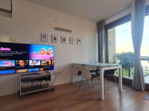a living room with a table and a flat screen tv at Elegante appartamento con vista a Cavallino Venezia in Cavallino-Treporti