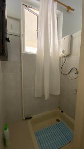a bathroom with a shower with a window and a blue mat at 2 Bedroom Apartment 250 meters from the Beach in Poste Lafayette