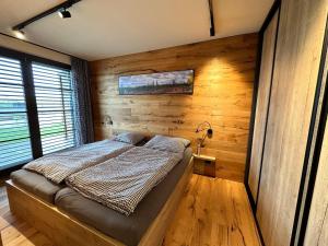 1 dormitorio con 1 cama y pared de madera en Holiday Home Říčky v Orlických horách E34 by Interhome, en Říčky