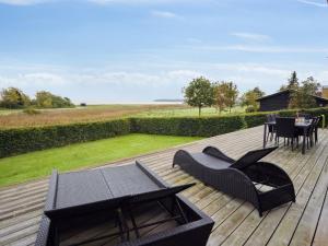 een houten terras met stoelen en een tafel erop bij Holiday Home Nora - 100m from the sea in SE Jutland by Interhome in Sønderby