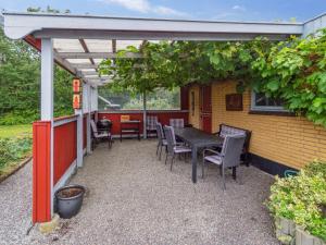 a patio with a table and chairs under a pergola at Holiday Home Ravn - 3-3km from the sea in Bornholm by Interhome in Vester Sømarken