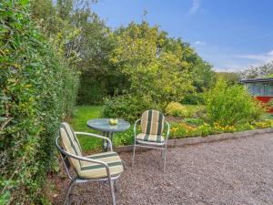 two chairs and a table in a garden at Holiday Home Ravn - 3-3km from the sea in Bornholm by Interhome in Vester Sømarken