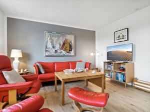 a living room with a red couch and a table at Holiday Home Ravn - 3-3km from the sea in Bornholm by Interhome in Vester Sømarken