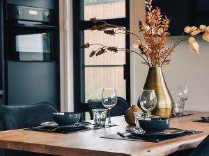 a wooden table with glasses and a vase on it at Holiday Home Villa Nautica 6 persoons by Interhome in Loosdrecht