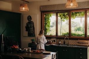a woman standing in a kitchen looking out the window at Converted Barn - Tiger House Hermitage in Havelock North