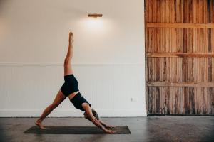 a woman doing a handstand on a yoga mat at Converted Barn - Tiger House Hermitage in Havelock North