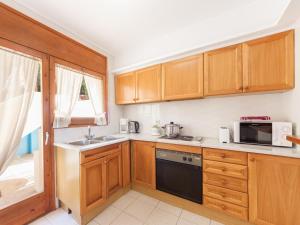 een keuken met houten kasten, een wastafel en een magnetron bij Apartment Melis III C3 by Interhome in Pals