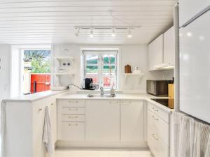 a white kitchen with white cabinets and a sink at Apartment Heidel - 400m from the sea in NW Jutland by Interhome in Skagen