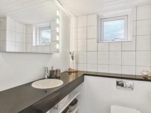 W białej łazience znajduje się umywalka i lustro. w obiekcie Apartment Heidel - 400m from the sea in NW Jutland by Interhome w mieście Skagen