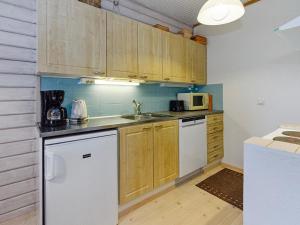 a kitchen with wooden cabinets and a white dishwasher at Holiday Home Kulta-käkönen 3 by bomba by Interhome in Nurmes