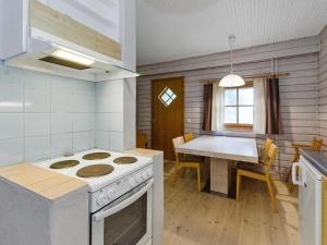 a kitchen with a stove and a dining table at Holiday Home Kulta-käkönen 3 by bomba by Interhome in Nurmes